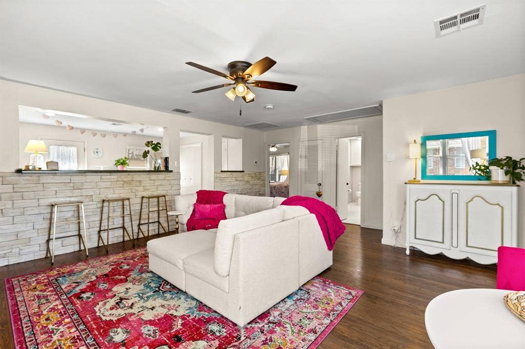 2425 S 2nd Street, Waco, TX 76706 Living area featuring wood-finish flooring, a stacked stone accent wall with a bar-height counter, and a ceiling fan with integrated lighting