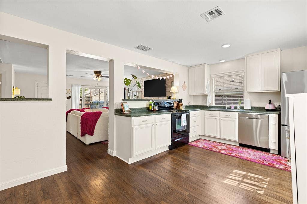 2425 S 2nd Street, Waco, TX 76706 Kitchen featuring white cabinetry, solid-surface countertops, wood-finish flooring, and stainless steel appliances