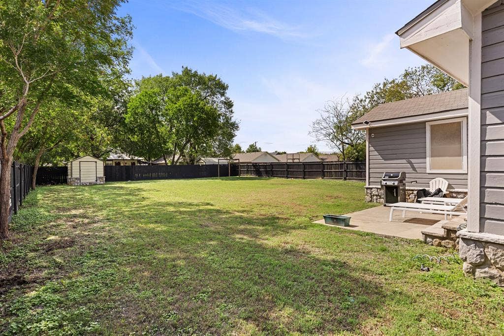 2425 S 2nd Street, Waco, TX 76706 Expansive backyard featuring a concrete patio, perimeter privacy fencing, mature trees, and a detached storage shed