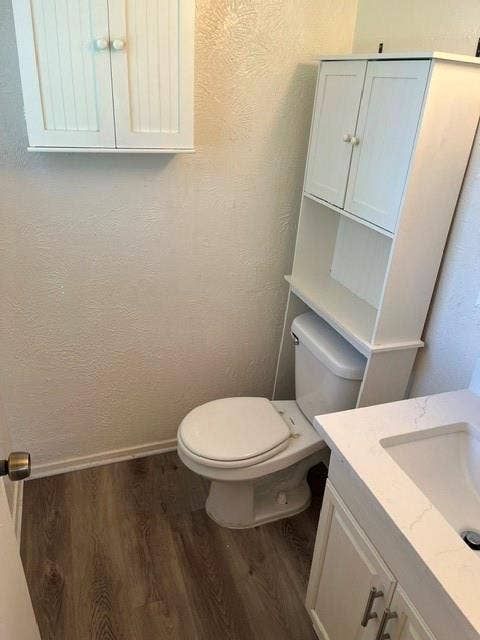 1236 Neptune Drive, Cedar Hill, TX 75104 Bathroom featuring wood-finish flooring, white cabinetry with beadboard detailing, an over-the-toilet storage unit, and a vanity with a white countertop and rectangular undermount sink