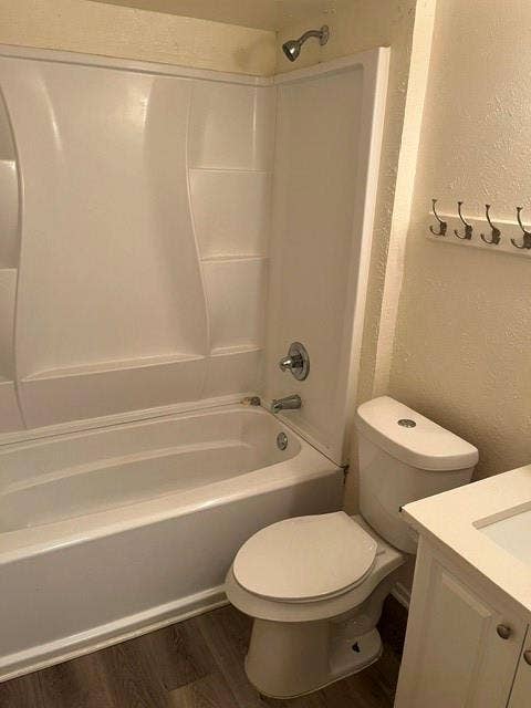 1236 Neptune Drive, Cedar Hill, TX 75104 Bathroom featuring a white molded tub-and-shower surround, wood-finish flooring, a wall-mounted hook rack, and a vanity cabinet