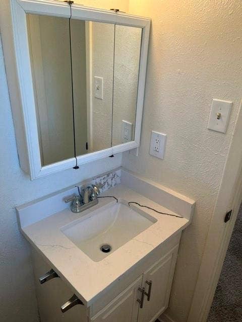 1236 Neptune Drive, Cedar Hill, TX 75104 Vanity featuring a white cabinet base, quartz countertop with integrated backsplash, rectangular drop-in sink, dual-handle metal faucet, and wall-mounted tri-fold mirrored medicine cabinet