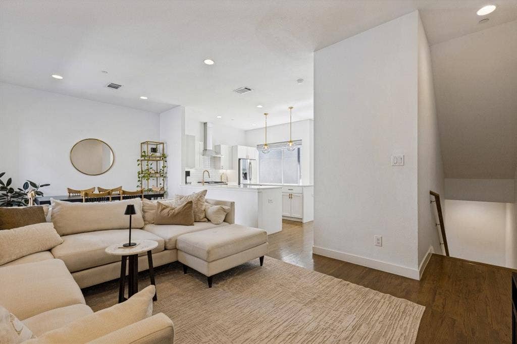 2107 Bennett Avenue, #20, Dallas, TX 75206 Open-concept living space featuring wood-finish flooring, recessed lighting, white cabinetry, an island with countertop seating, and a modern stairwell with a wooden handrail