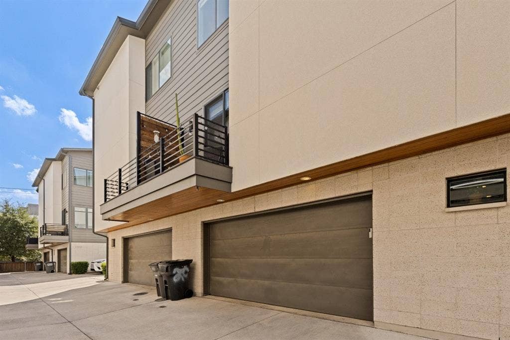2107 Bennett Avenue, #20, Dallas, TX 75206 Contemporary multi-story exterior featuring a mix of horizontal lap siding and smooth stucco finishes, a private balcony with horizontal metal railing, wood-accented soffits, and a multi-car garage with overhead doors