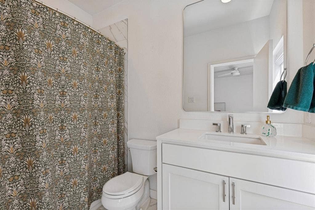 2107 Bennett Avenue, #20, Dallas, TX 75206 White vanity with a solid surface countertop, rectangular under-mount sink, polished chrome widespread faucet, and a large frameless rounded-corner mirror