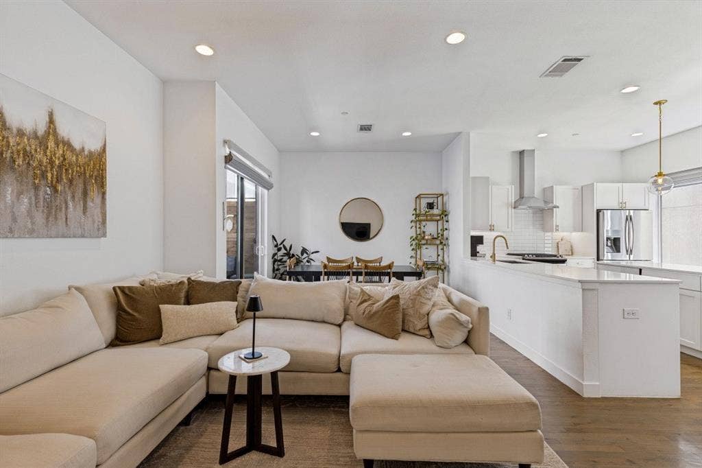 2107 Bennett Avenue, #20, Dallas, TX 75206 Open-concept living space featuring wood-finish flooring, recessed lighting, white cabinetry, a quartz waterfall-edge peninsula, and a stainless steel range hood