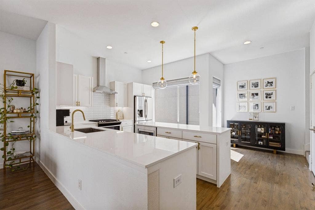 2107 Bennett Avenue, #20, Dallas, TX 75206 Kitchen featuring white shaker-style cabinetry, quartz countertops, a stainless steel chimney-style range hood, dual glass globe pendant lights, and wood-finish flooring