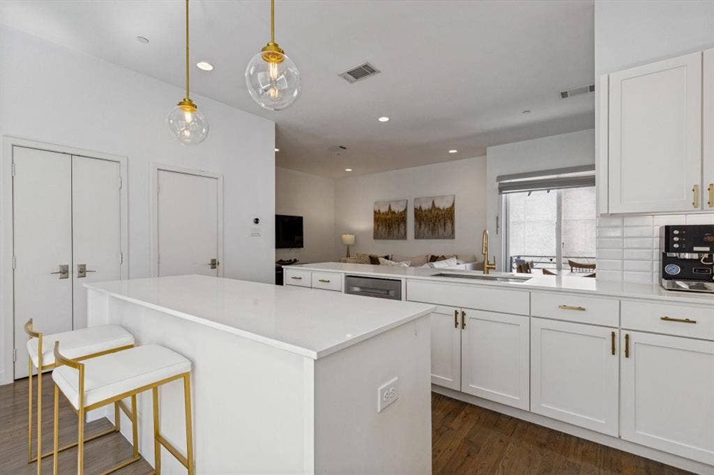 2107 Bennett Avenue, #20, Dallas, TX 75206 Kitchen featuring white cabinetry, quartz countertops, a subway tile backsplash, wood-finish flooring, and gold-toned hardware