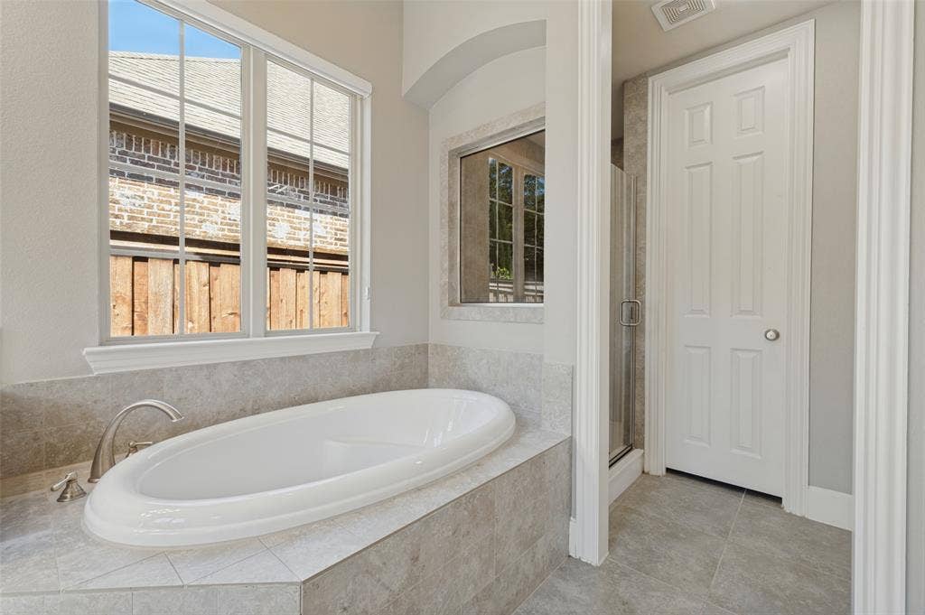 301 Longhorn Drive, McKinney, TX 75071 First floor primary suite with generous space and an ensuite bath featuring separate vanities, a soaking tub and separate shower.
