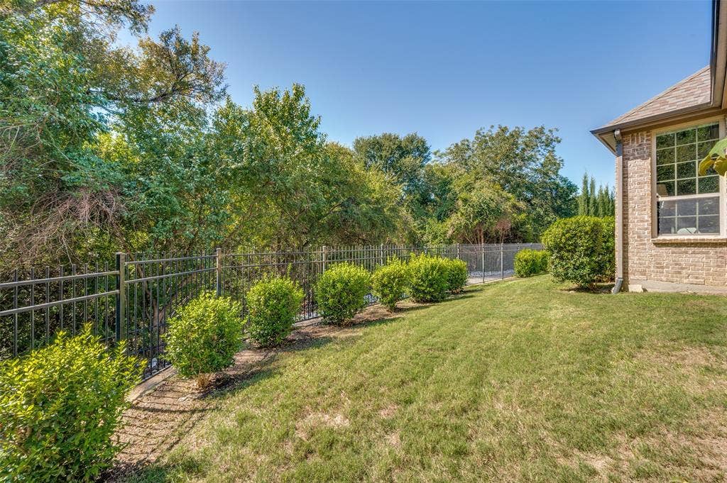 301 Longhorn Drive, McKinney, TX 75071 Covered patio with a wood burning fireplace overlooking the greenbelt and spacious backyard.