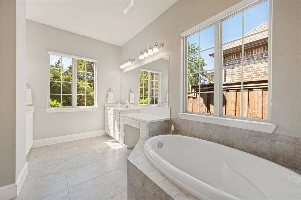 301 Longhorn Drive, McKinney, TX 75071 First floor primary suite with generous space and an ensuite bath featuring separate vanities, a soaking tub and separate shower.