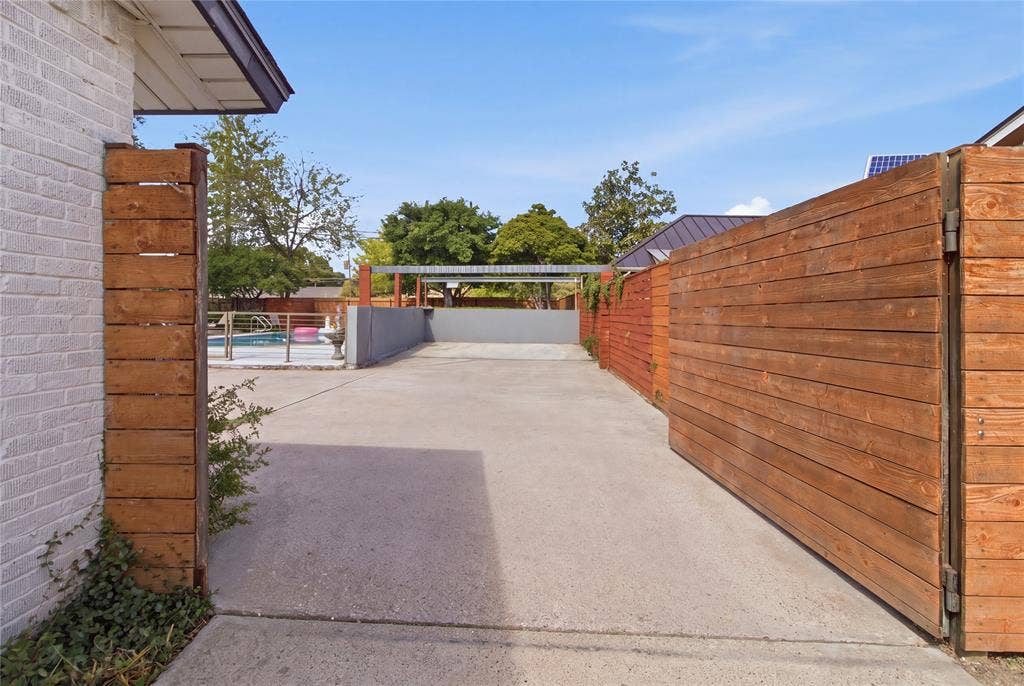 2712 Beechmont Place, Dallas, TX 75228 Beyond the horizontal wood privacy gate, the extended driveway opens into a generous paved parking area, offering convenient additional parking for vehicles and guests. The wood fencing complements the home's contemporary styling while providing separation from the street. With the swimming pool and outdoor entertaining areas nearby, this flexible space is especially convenient when hosting larger gatherings.