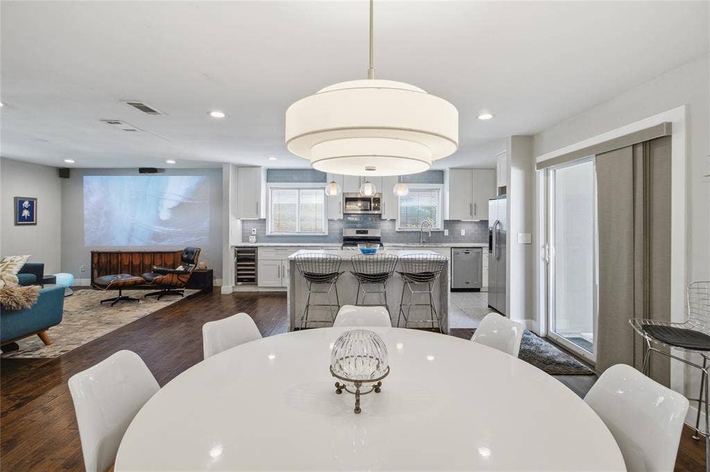 2712 Beechmont Place, Dallas, TX 75228 From the dining area, the home's thoughtful layout comes into focus, with the kitchen's generous island, abundant cabinetry, and stainless steel appliances framed by two windows. Sliding glass doors provide easy access to the outdoors, while the adjoining living room offers a comfortable place to unwind with a favorite movie. The open design creates a bright, connected environment without sacrificing the individual character of each space.