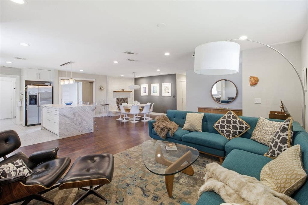 2712 Beechmont Place, Dallas, TX 75228 Designed for both everyday living and entertaining, the open-concept floor plan seamlessly connects the living room, dining area, and kitchen. A striking waterfall-edge kitchen island provides a natural gathering place, while the wood-burning fireplace with gas starter adds architectural character to the dining area. Rich, warm-toned flooring unifies the spaces, complemented by contemporary finishes and mid-century modern influences. The thoughtful layout provides an easy flow between cooking, dining, and relaxing while maintaining a sense of connection throughout the main living areas.
