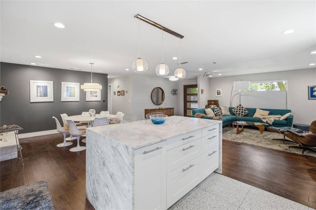 2712 Beechmont Place, Dallas, TX 75228 From the kitchen, enjoy an inviting view of the home's open living and dining areas. The impressive quartz waterfall island offers generous workspace and storage, while the rich flooring, contemporary lighting, and abundant natural light create a welcoming atmosphere. The connected layout makes it easy to move between cooking, dining, and relaxing at home.