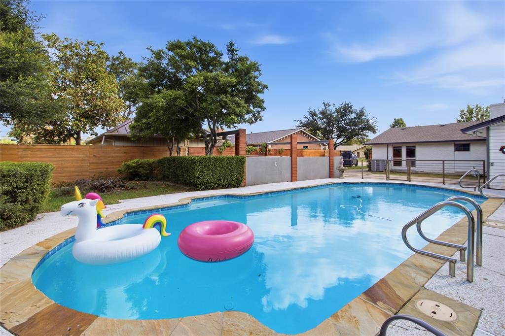 2712 Beechmont Place, Dallas, TX 75228 Who’s ready for a pool party? The sparkling swimming pool takes center stage, with colorful floats adding a playful touch to this backyard retreat. Mature trees, neatly trimmed hedges, and attractive wood privacy fencing create a lush, inviting setting. Beyond the pool, an additional grassy area offers even more outdoor space to enjoy, whether relaxing in the sunshine or gathering with friends and family.