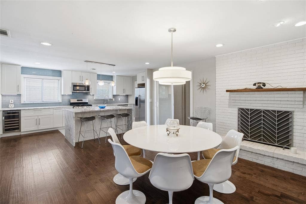 2712 Beechmont Place, Dallas, TX 75228 The beautifully appointed kitchen flows effortlessly into the dining area, creating an inviting space for cooking and conversation. A striking waterfall-edge island offers casual seating for three, while crisp white shaker-style cabinetry with soft-close drawers, a blue-gray subway tile backsplash, stainless steel appliances, and a built-in beverage refrigerator combine style with everyday functionality. The open layout keeps the kitchen connected to the dining and living areas, making everything from meal preparation to casual dining feel effortless.