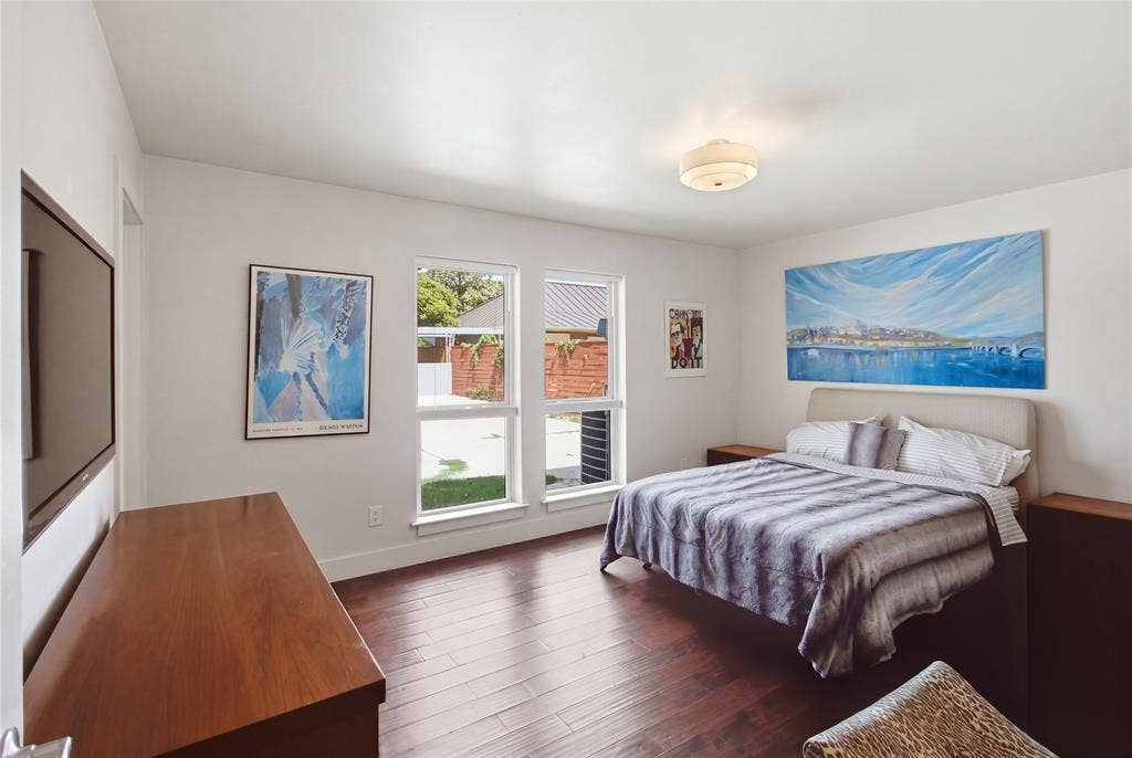 2712 Beechmont Place, Dallas, TX 75228 The spacious primary bedroom welcomes natural light through two large windows overlooking the backyard. Rich, warm-toned flooring, neutral walls, and ample space for bedroom furnishings create a comfortable retreat with a clean, contemporary feel.
