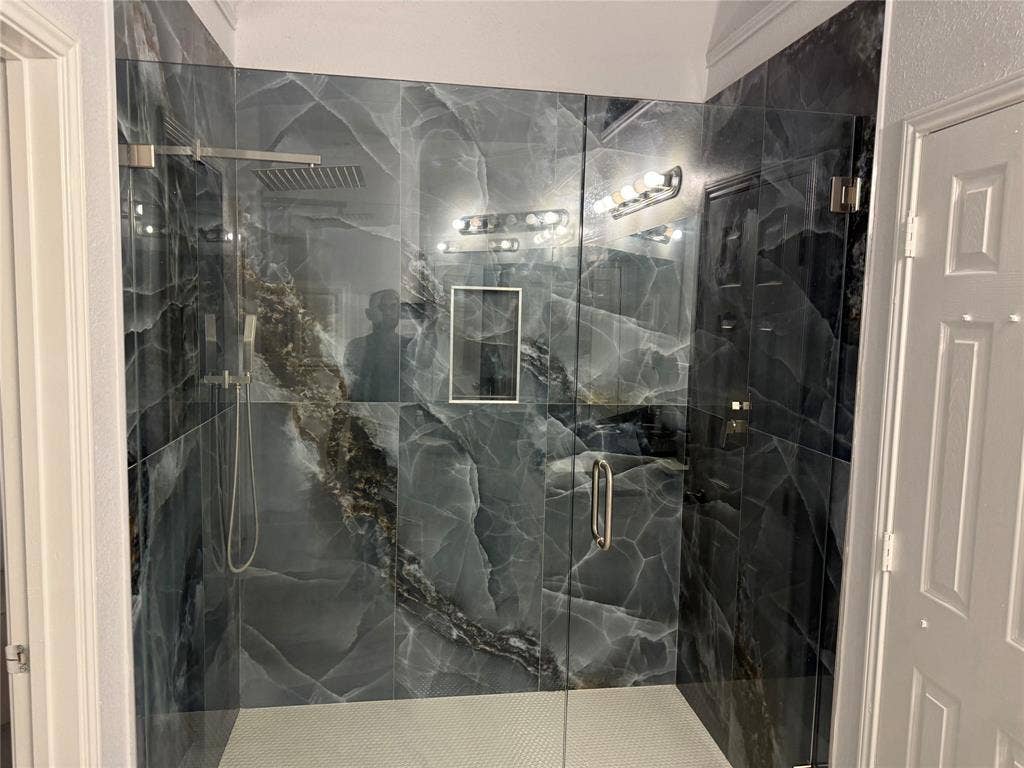 14 Heritage Way, Allen, TX 75002 Walk-in shower featuring large-format dark patterned wall tile, frameless glass enclosure, built-in recessed niche, rainfall showerhead, and hexagon-tiled flooring