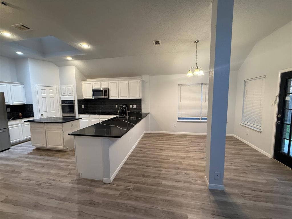 14 Heritage Way, Allen, TX 75002 Kitchen featuring wood-finish flooring, a central island with a dark countertop, white cabinetry, dark tiled backsplash, and recessed lighting