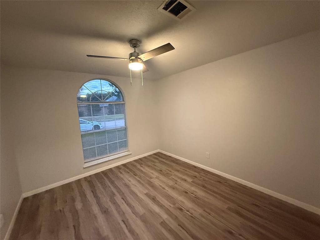 14 Heritage Way, Allen, TX 75002 Interior room featuring wood-finish flooring, an arched window, and a ceiling-mounted light fixture with a fan