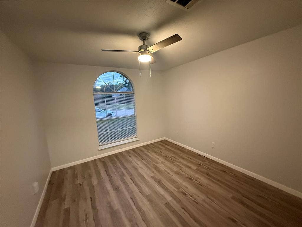 14 Heritage Way, Allen, TX 75002 Interior space featuring wood-finish flooring, an arched window with grid mullions, and a central ceiling fan with integrated lighting