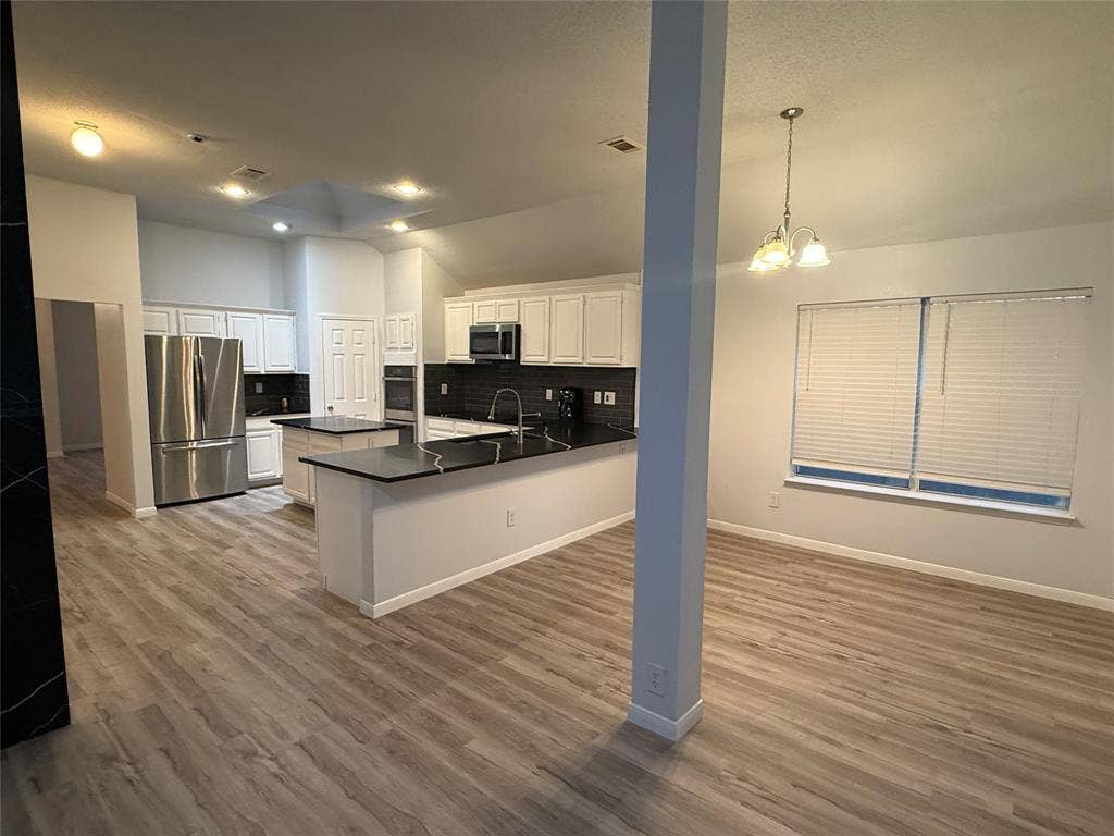 14 Heritage Way, Allen, TX 75002 Kitchen featuring white shaker-style cabinetry, dark stone countertops, stainless steel appliances, wood-finish flooring, and vaulted ceilings