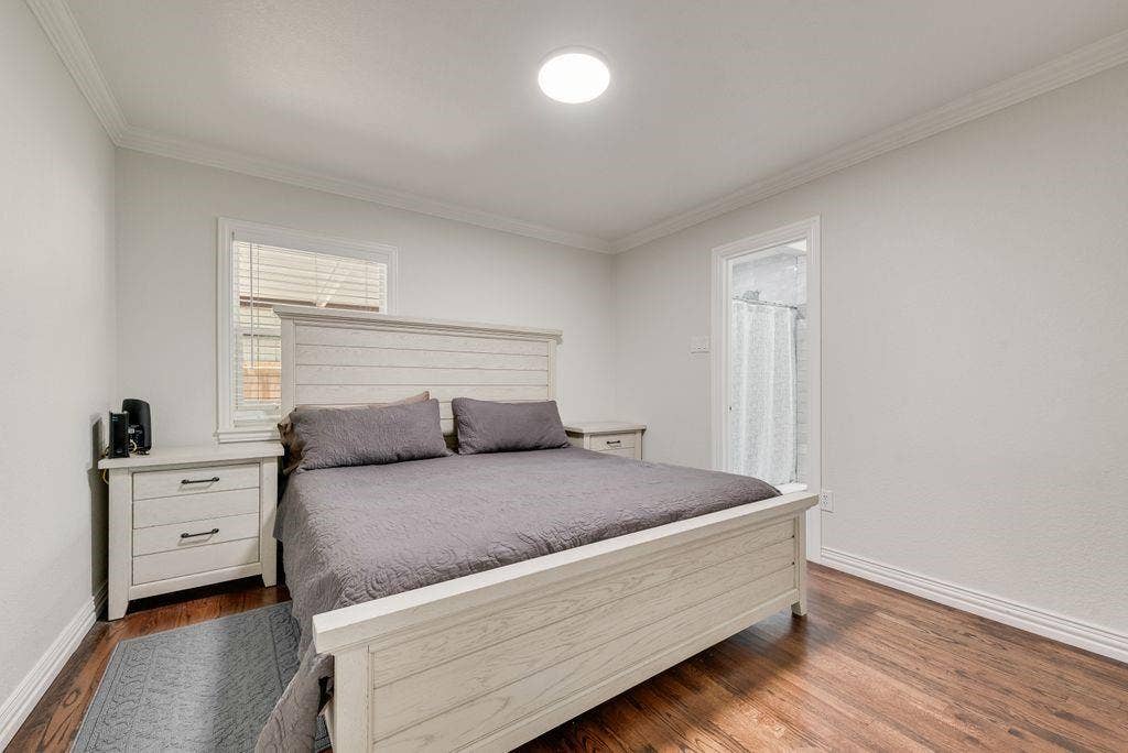 2815 Anzio Drive, Dallas, TX 75224 Bedroom featuring wood-finish flooring, crown molding, a flush-mount ceiling light fixture, and a window with white horizontal blinds