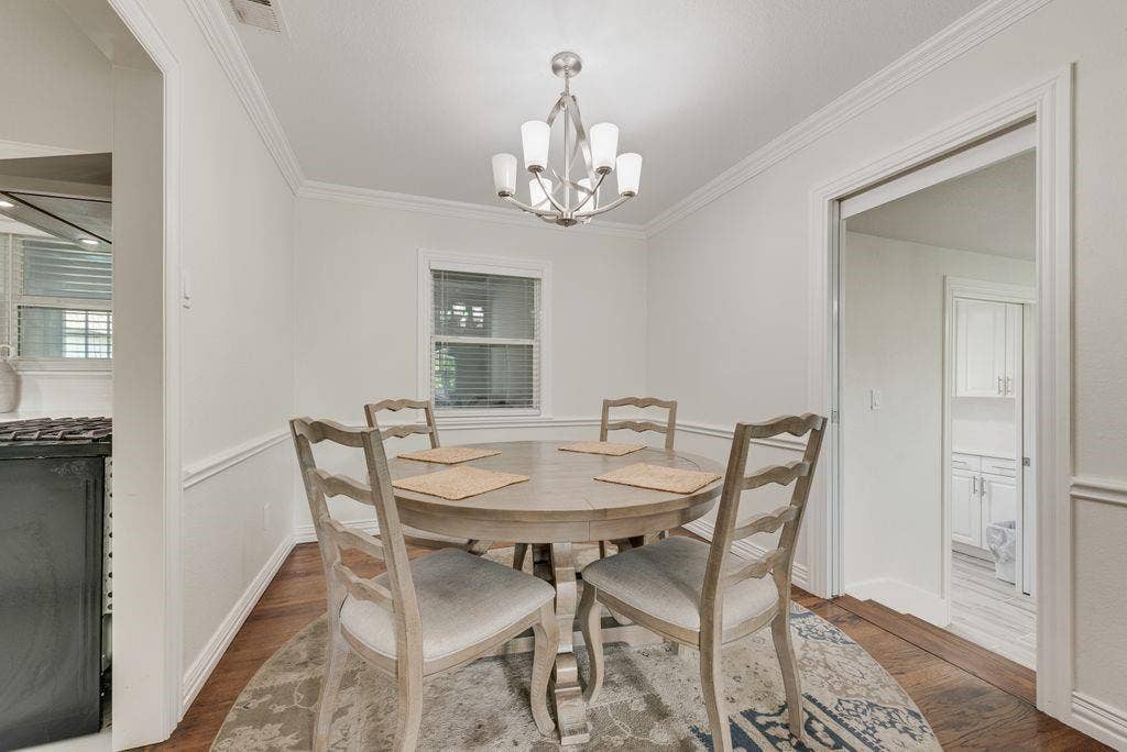 2815 Anzio Drive, Dallas, TX 75224 Dining area featuring wood-finish flooring, crown molding, chair rail trim, and a multi-arm chandelier