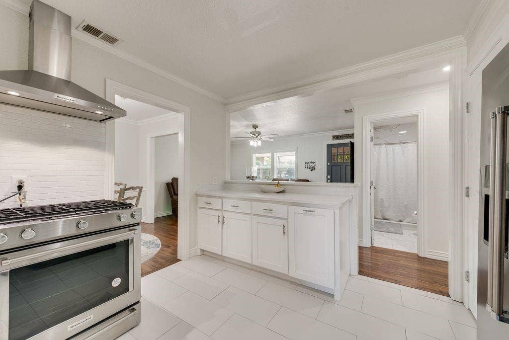 2815 Anzio Drive, Dallas, TX 75224 Kitchen featuring white shaker cabinetry, stone-finish countertops, stainless steel range with a professional-style chimney hood, and large-format tile flooring