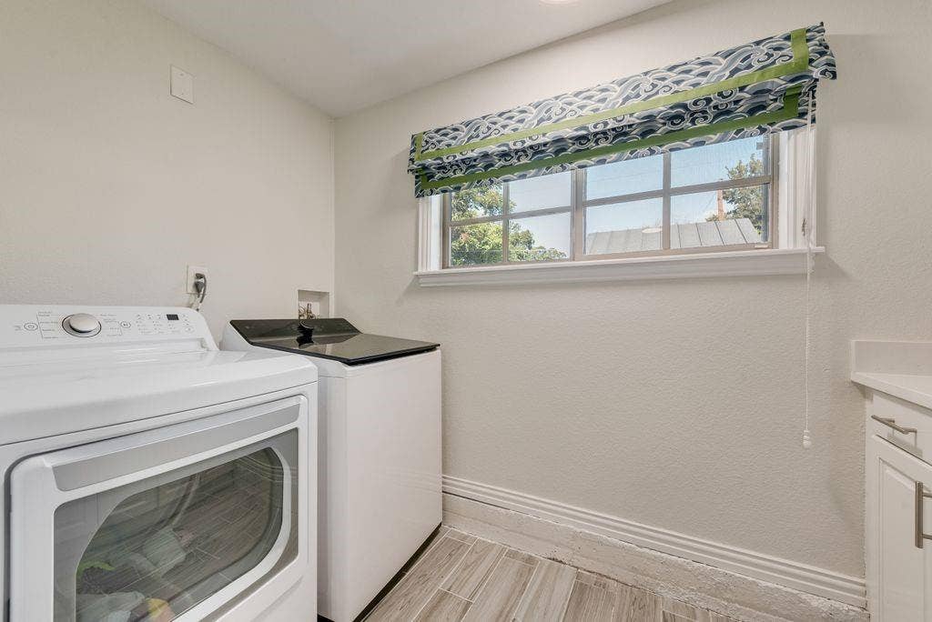 2815 Anzio Drive, Dallas, TX 75224 Laundry room featuring neutral wall finishes, tile flooring, a window with a valance, and white cabinetry with a solid-surface countertop