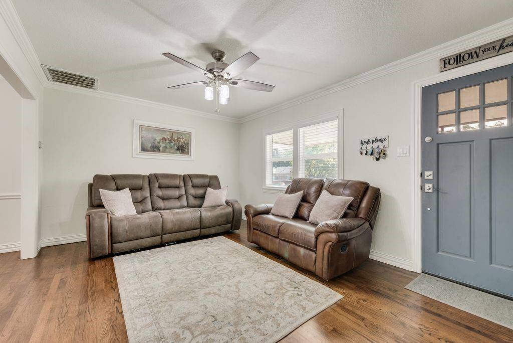 2815 Anzio Drive, Dallas, TX 75224 Wood-finish flooring, blue painted front door with multi-pane glass inserts, crown molding, and a multi-blade ceiling fan with integrated lighting