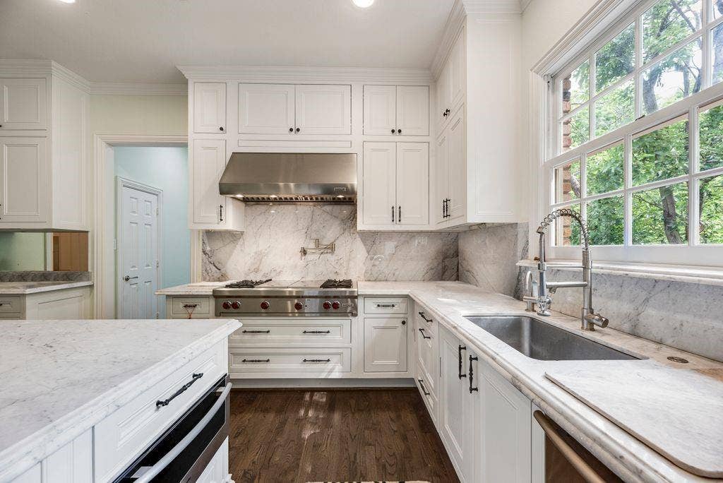 1418 Yakimo Drive, Dallas, TX 75208 Kitchen featuring shaker-style cabinetry, stone countertops and backsplash, stainless steel gas range with a matching range hood, wall-mounted pot filler, and wood-finish flooring