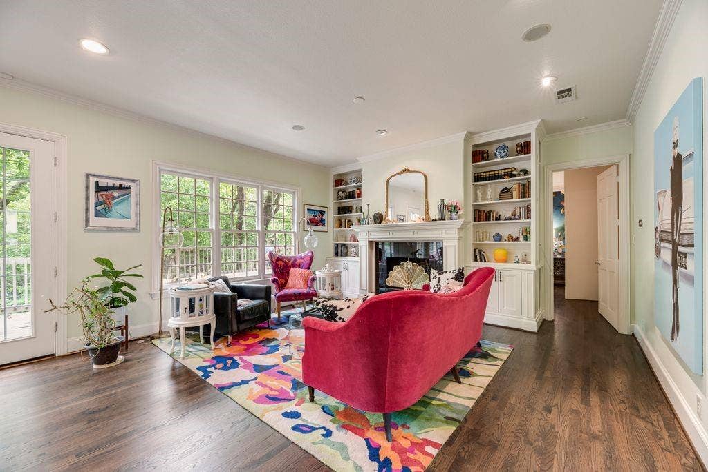 1418 Yakimo Drive, Dallas, TX 75208 Living room featuring dark wood-finish flooring, a traditional fireplace with a decorative mantel, and built-in floor-to-ceiling shelving