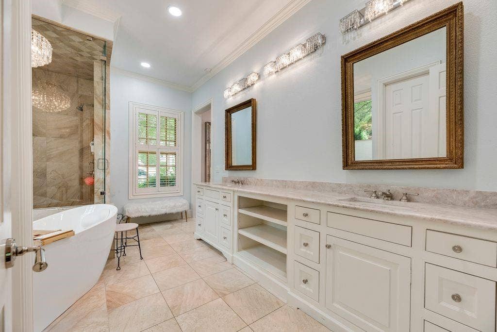 1418 Yakimo Drive, Dallas, TX 75208 Bathroom featuring a dual-sink vanity with stone countertop, freestanding soaking tub, glass-enclosed shower with stone tile surround, and tile flooring