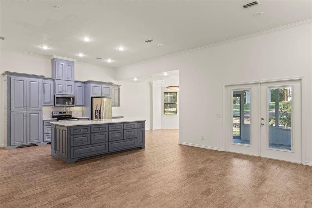 409 Oak Creek Drive, Tool, TX 75143 Open-concept living and kitchen area with high ceilings, a large center island, and French doors leading to the screened porch.