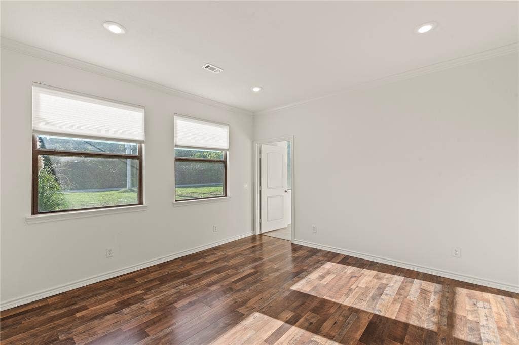 409 Oak Creek Drive, Tool, TX 75143 Ensuite bedroom two featuring wood flooring, recessed lighting, and large windows overlooking the backyard.