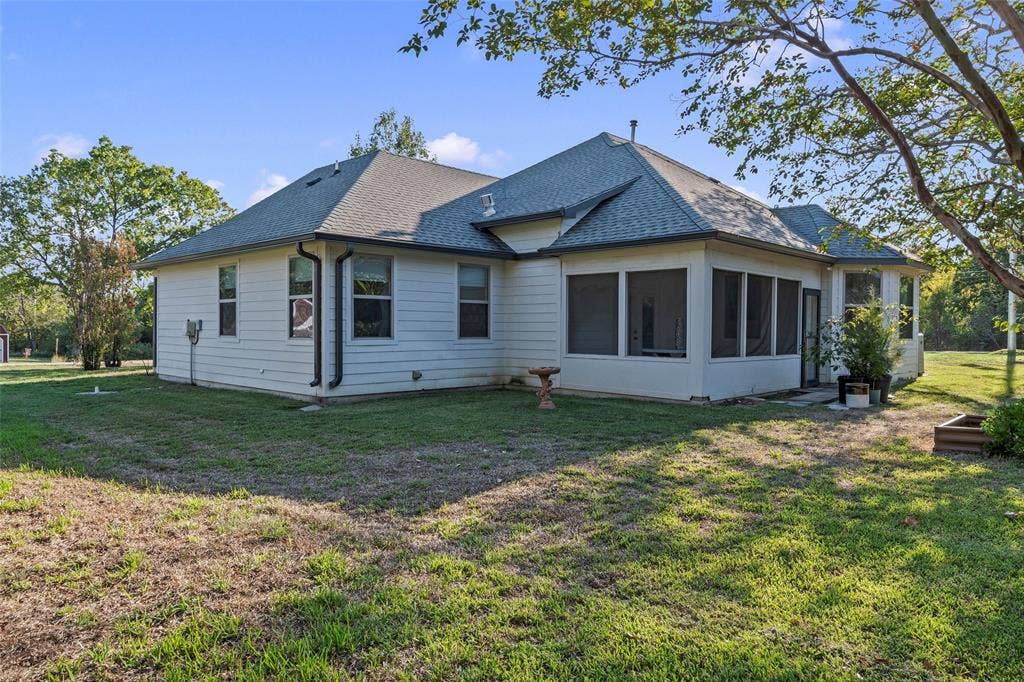 409 Oak Creek Drive, Tool, TX 75143 Rear exterior view of the home featuring an screened in back patio and part of the spacious backyard.