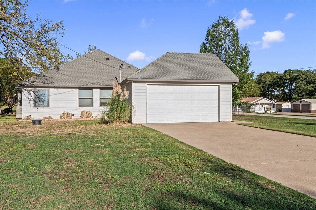 409 Oak Creek Drive, Tool, TX 75143 Side exterior showcasing the attached two-car garage and concrete driveway.
