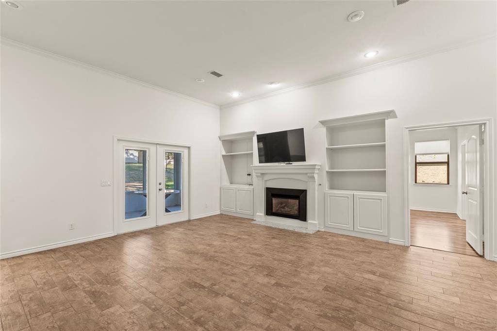 409 Oak Creek Drive, Tool, TX 75143 Living room featuring a fireplace, custom built-in shelving, and French doors opening to the screened porch.