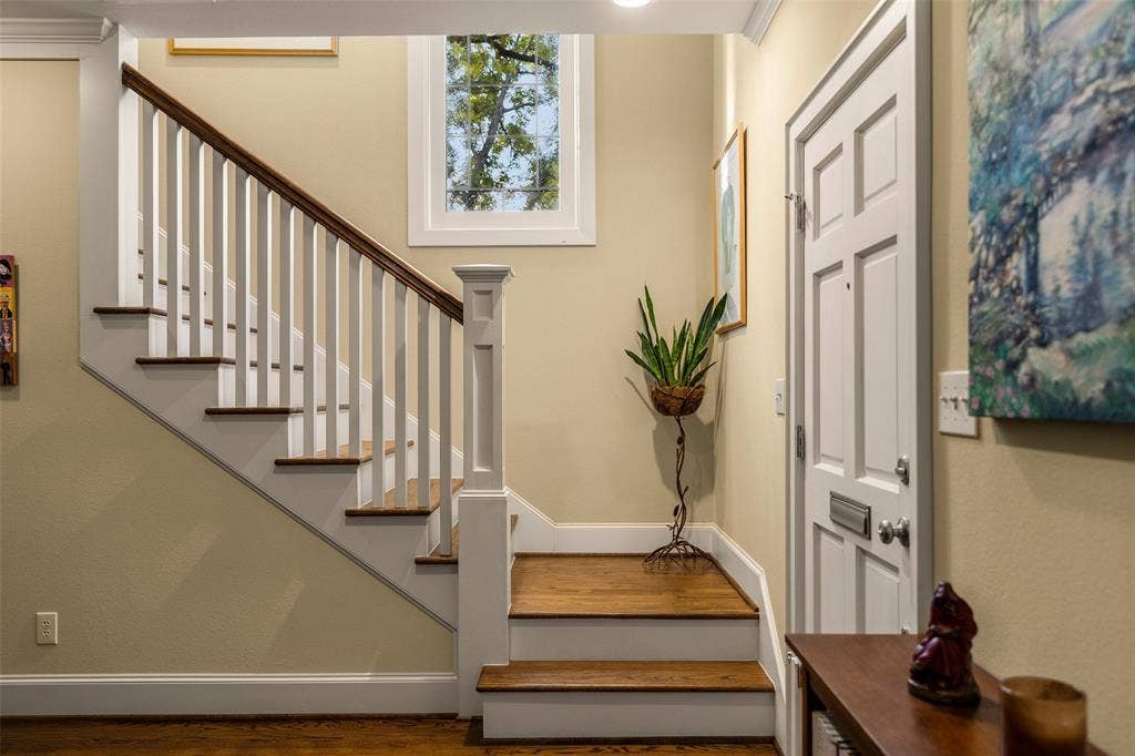 6020 Tremont Street, Dallas, TX 75214 Foyer featuring a staircase with white balusters and wood-finish treads, a multi-pane fixed window, and a panelled exterior door with a built-in mail slot