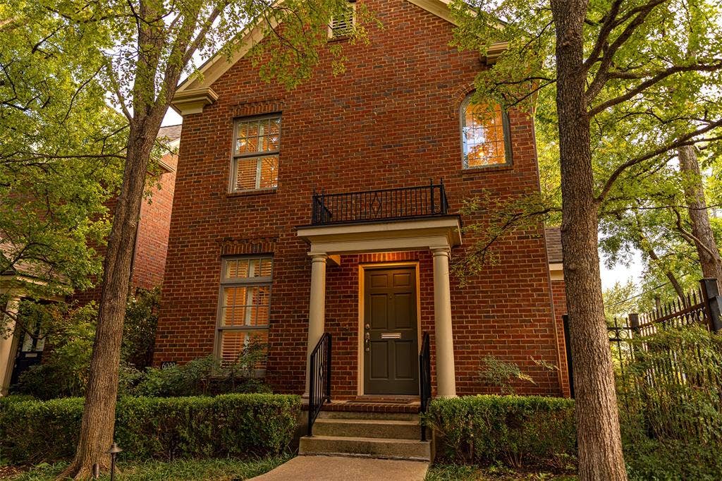6020 Tremont Street, Dallas, TX 75214 Traditional brick exterior featuring a covered entryway with classical columns, a second-story wrought iron balcony, and arched window detailing