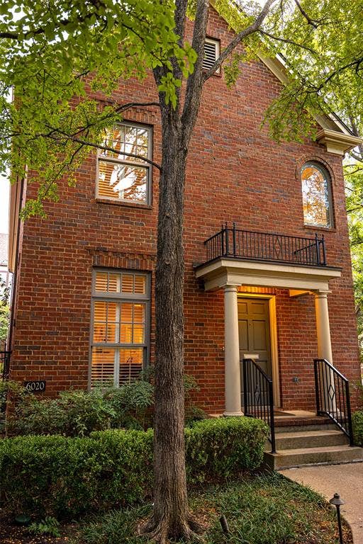 6020 Tremont Street, Dallas, TX 75214 Two-story brick exterior featuring a covered entryway with columns, a wrought-iron Juliet balcony, and a prominent arched window