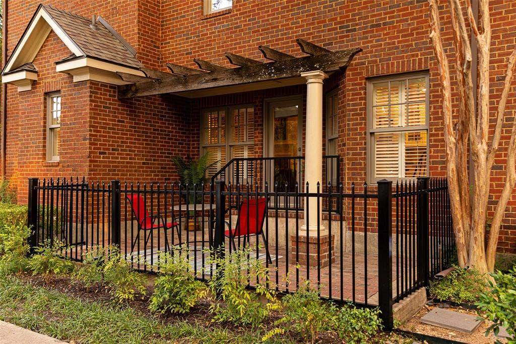 6020 Tremont Street, Dallas, TX 75214 Red brick exterior featuring a covered patio, wooden pergola, decorative column support, and black metal fencing