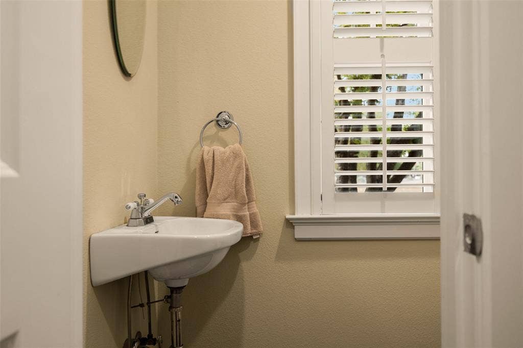 6020 Tremont Street, Dallas, TX 75214 Wall-mounted ceramic pedestal sink, chrome hardware, and white plantation shutters