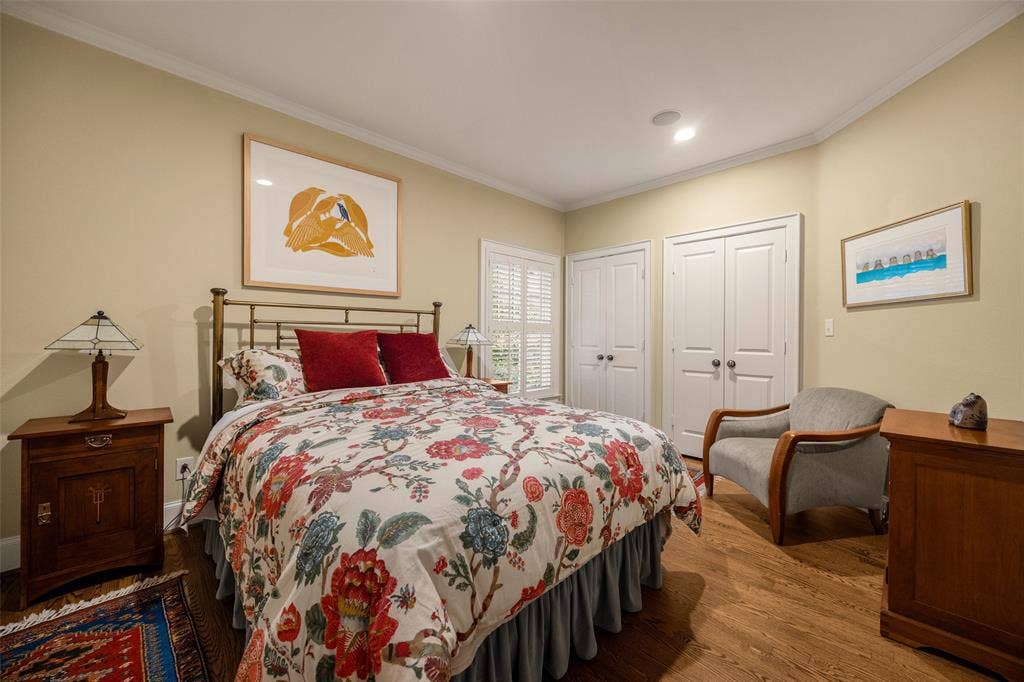 6020 Tremont Street, Dallas, TX 75214 Bedroom featuring wood-finish flooring, crown molding, dual-panel closet doors, and interior shutters