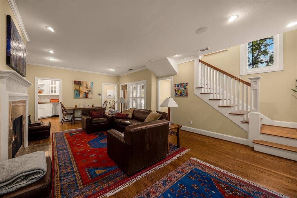 6020 Tremont Street, Dallas, TX 75214 Living area featuring wood-finish flooring, a fireplace with a decorative mantel, recessed lighting, and a staircase with white balusters and wood treads