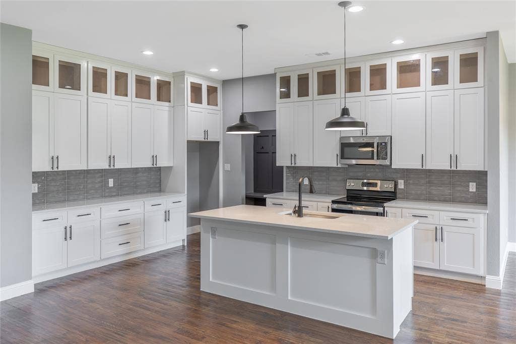 10560 Lago Vista, Quinlan, TX 75474 Kitchen featuring appliances with stainless steel finishes, glass insert cabinets, hanging light fixtures, tasteful backsplash, and dark wood finished floors