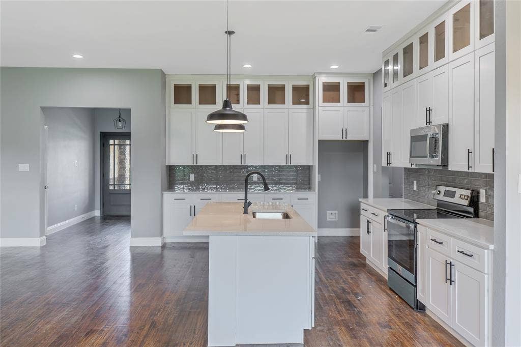10560 Lago Vista, Quinlan, TX 75474 Kitchen with stainless steel appliances, pendant lighting, a center island with sink, tasteful backsplash, and light stone countertops