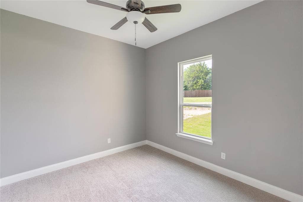 10560 Lago Vista, Quinlan, TX 75474 Carpeted empty room with baseboards and a ceiling fan